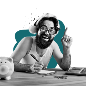 Happy man wearing a Santa hat, holding a pen, and writing in a notebook next to a piggy bank and a laptop, symbolizing New Year’s resolutions and financial planning.
