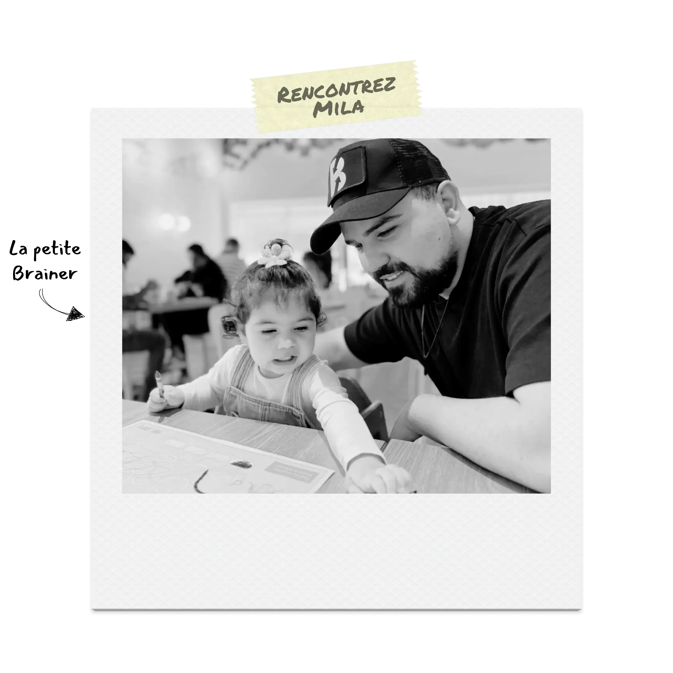 Le Brainer sourit à côté de sa fille pendant qu’elle rit et dessine sur une feuille.